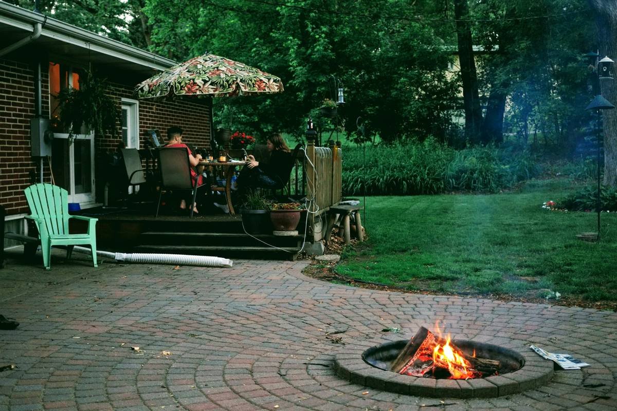 Diagram comparing standard coffee table height (16-18in) vs bar-height fire pit accessory (40-42in) showing ergonomic arm position and drink placement